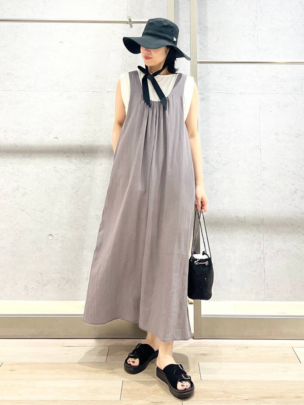 ブラック系のショルダーバッグ、ブラック系のサンダル、ホワイト系のTシャツ/カットソーを着用したレディースの夏コーディネートの3枚目の写真