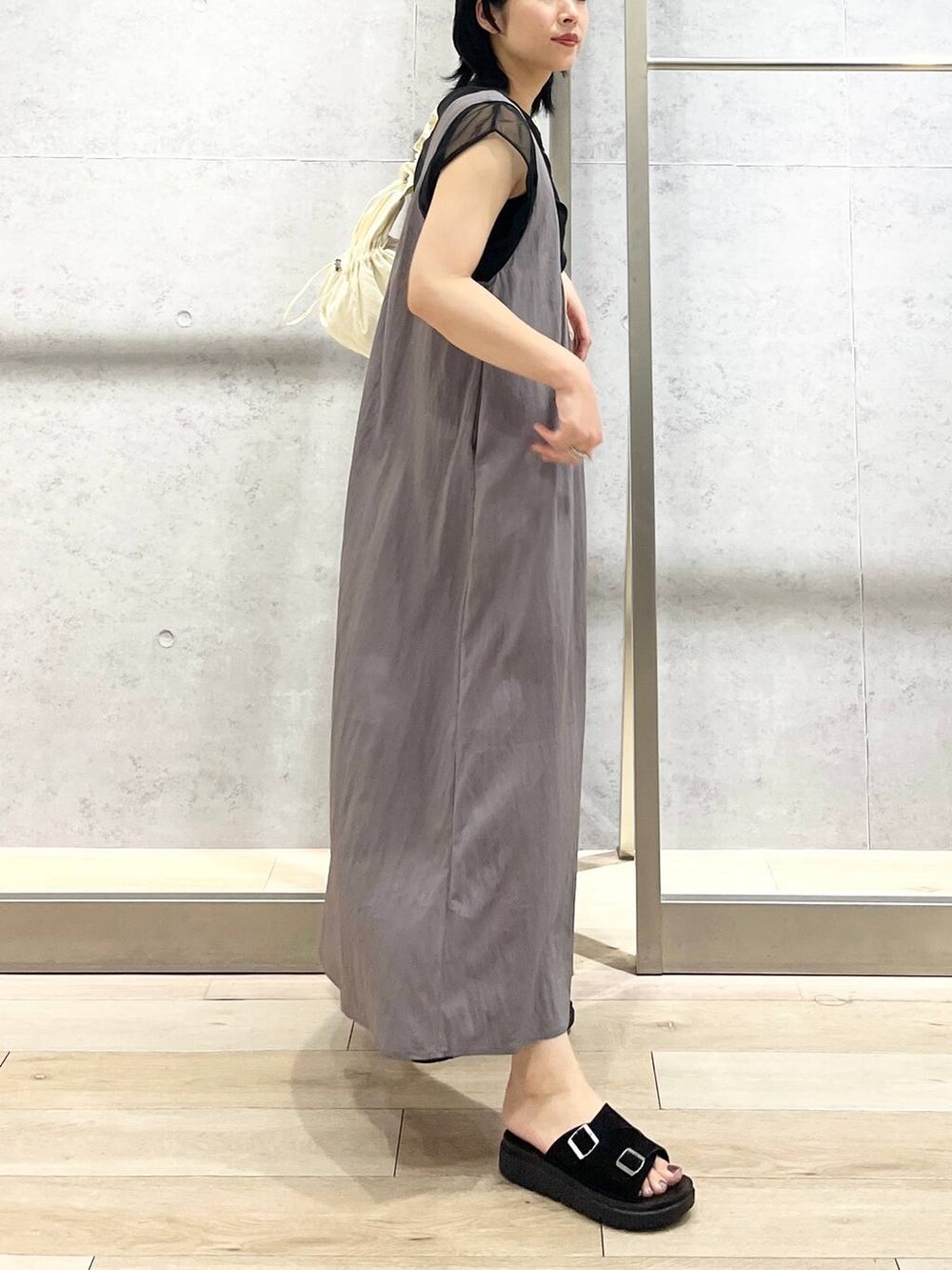ブラック系のサンダル、グレー系のジャンパースカート、ホワイト系のショルダーバッグを着用したレディースの夏コーディネートの4枚目の写真