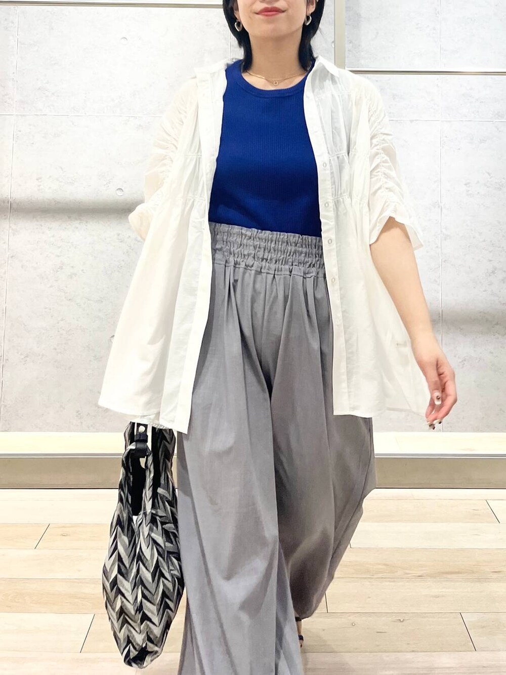 ブラック系のサンダル、ブラック系のハンドバッグ、グレー系のスラックスを着用したレディースの夏コーディネートの9枚目の写真