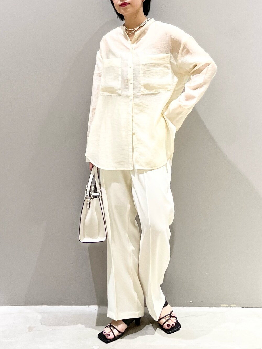 ホワイト系のシャツ/ブラウス、ホワイト系のスラックス、ホワイト系のショルダーバッグを着用したレディースの夏コーディネートの2枚目の写真
