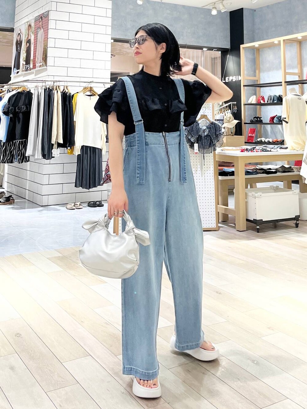 ホワイト系のサンダル、ブルー系のデニムパンツ、シルバー系のショルダーバッグを着用したレディースの夏コーディネートの7枚目の写真