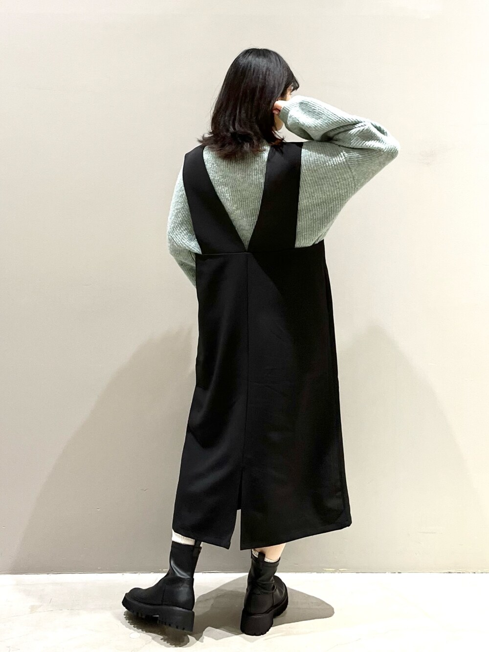 ホワイト系のバッグ、ブラック系のブーツ、グリーン系のニット/セーターを着用したレディースの冬コーディネートの2枚目の写真