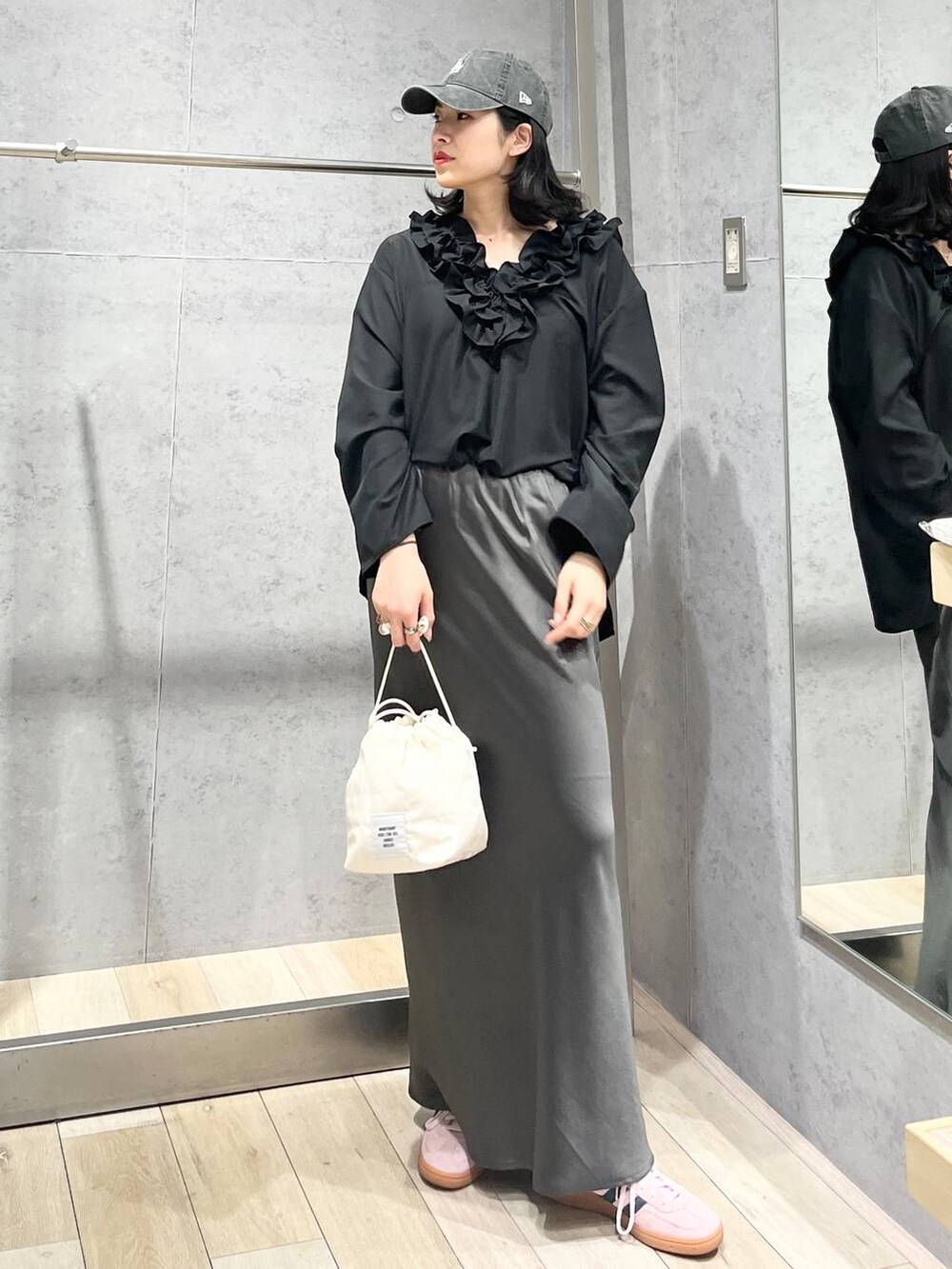 グレー系のスカート、ホワイト系のショルダーバッグ、ブラック系のキャップを着用したレディースの春コーディネートの3枚目の写真