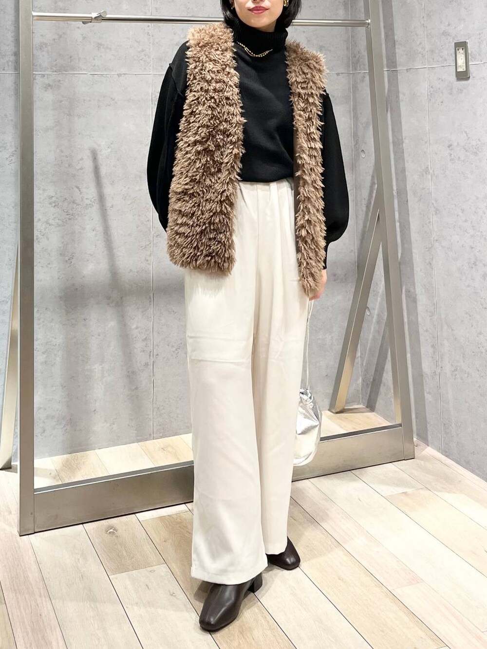 ブラック系のニット/セーター、ブラウン系のブーツ、ホワイト系のその他パンツを着用したレディースの秋コーディネートの2枚目の写真