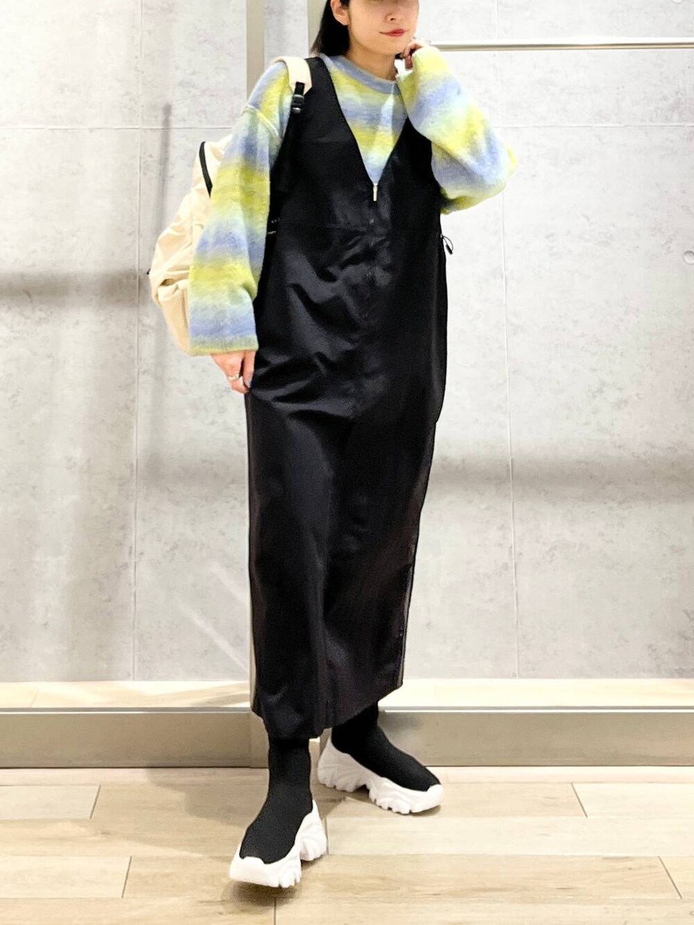 ホワイト系のバックパック/リュック、ブラック系のブーツ、ブラック系のジャンパースカートを着用したレディースの冬コーディネートの7枚目の写真