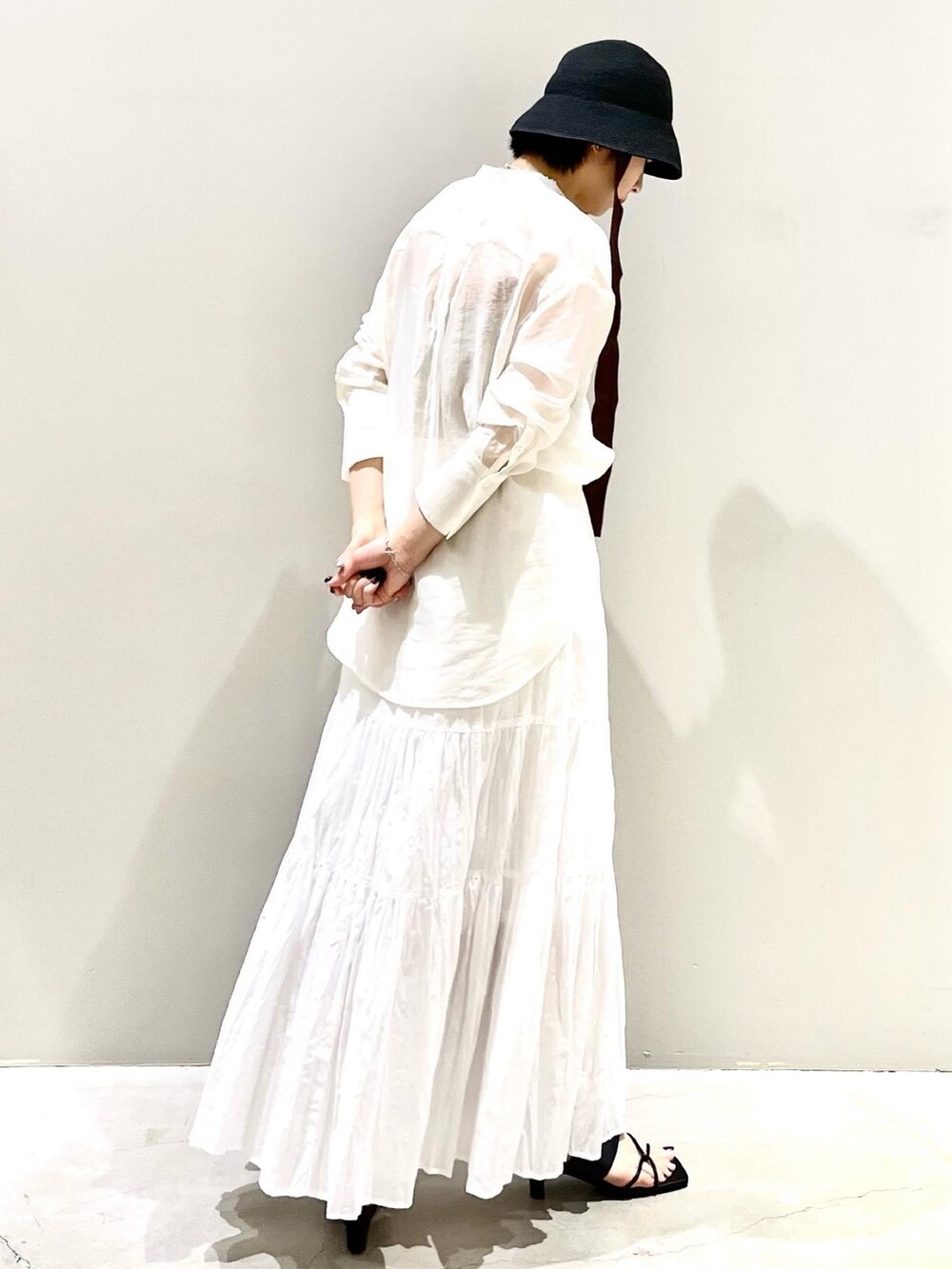 ホワイト系のスカート、ホワイト系のシャツ/ブラウス、ブラック系のサンダルを着用したレディースの夏コーディネートの6枚目の写真