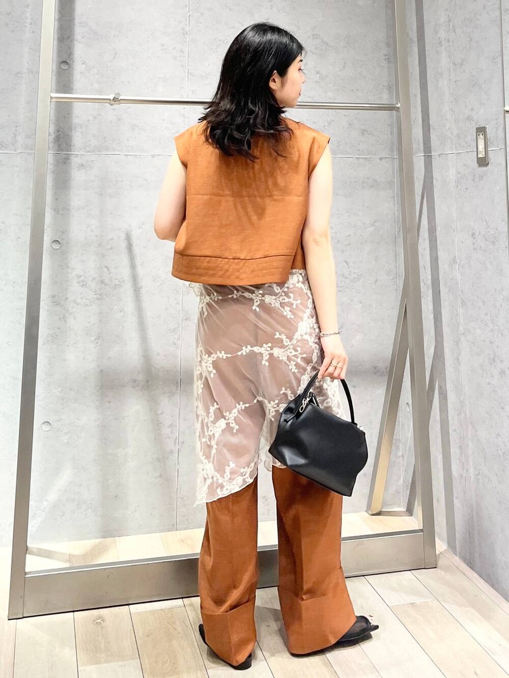 ブラック系のサンダル、オレンジ系のシャツ/ブラウス、ブラック系のショルダーバッグを着用したレディースの夏コーディネートの5枚目の写真