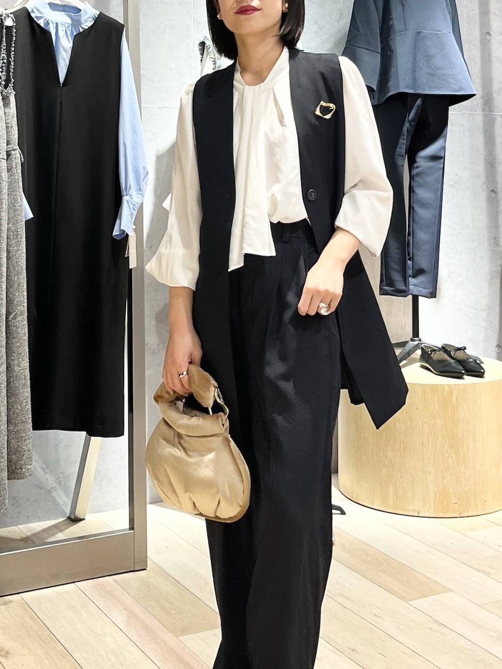 ベージュ系のハンドバッグ、ホワイト系のシャツ/ブラウス、ブラック系のパンプスを着用したレディースの冬コーディネートの2枚目の写真