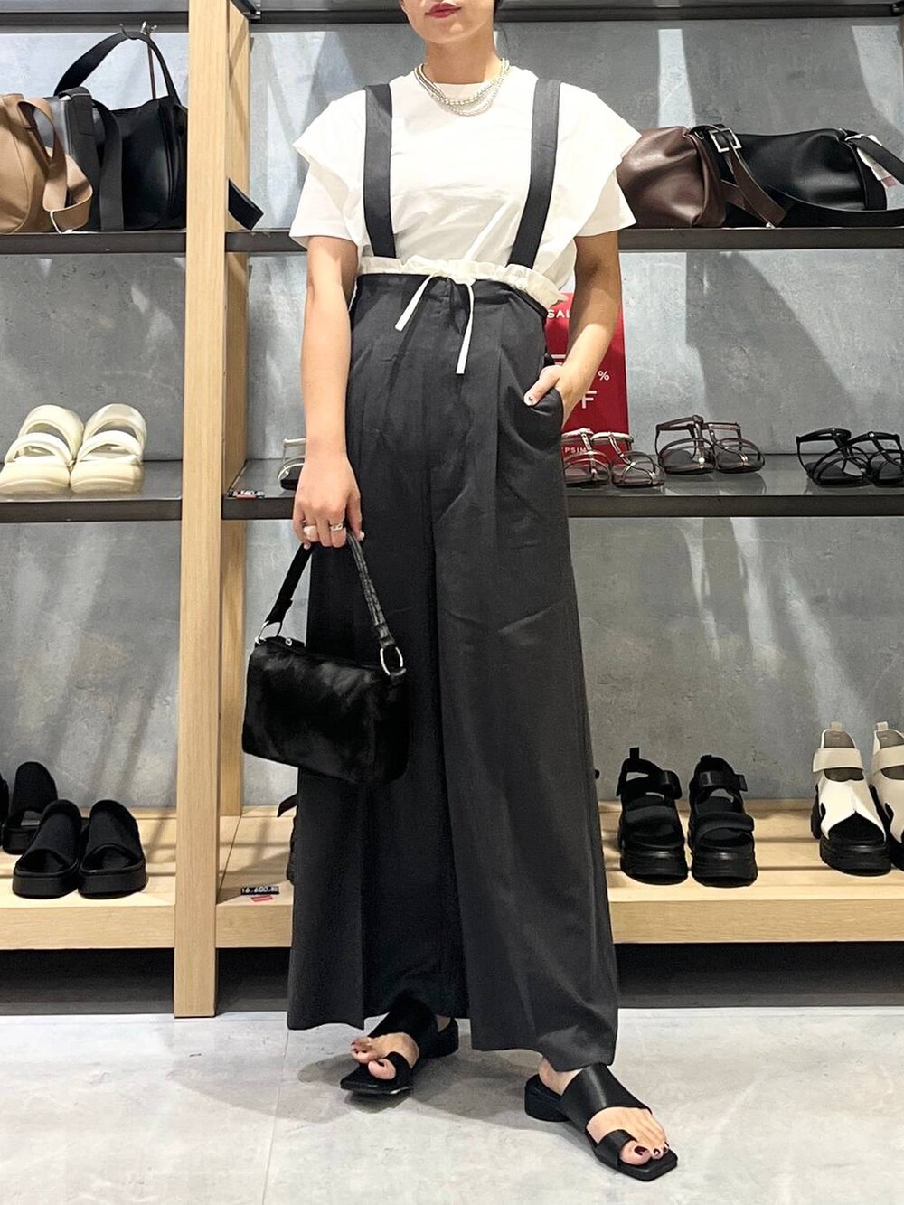 ブラック系のハンドバッグ、ブラック系のサンダル、ホワイト系のTシャツ/カットソーを着用したレディースの夏コーディネートの3枚目の写真