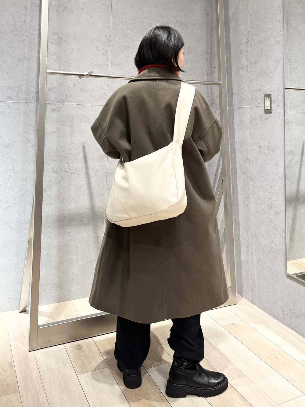 レッド系のニット/セーター、グリーン系のチェスターコート、ブラック系のブーツを着用したレディースの冬コーディネートの5枚目の写真