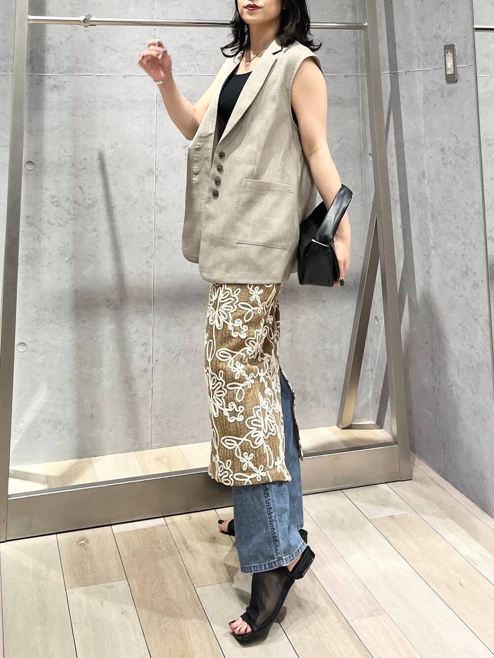 ブルー系のデニムパンツ、ブラック系のハンドバッグ、ブラック系のサンダルを着用したレディースの春コーディネートの3枚目の写真
