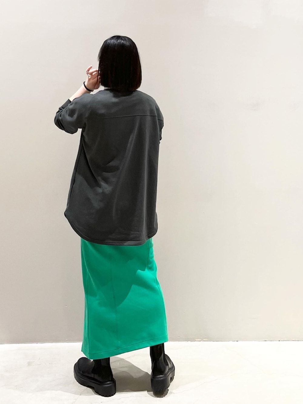 グレー系のTシャツ/カットソー、グリーン系のスカート、ブラック系のブーツを着用したレディースの春コーディネートの3枚目の写真