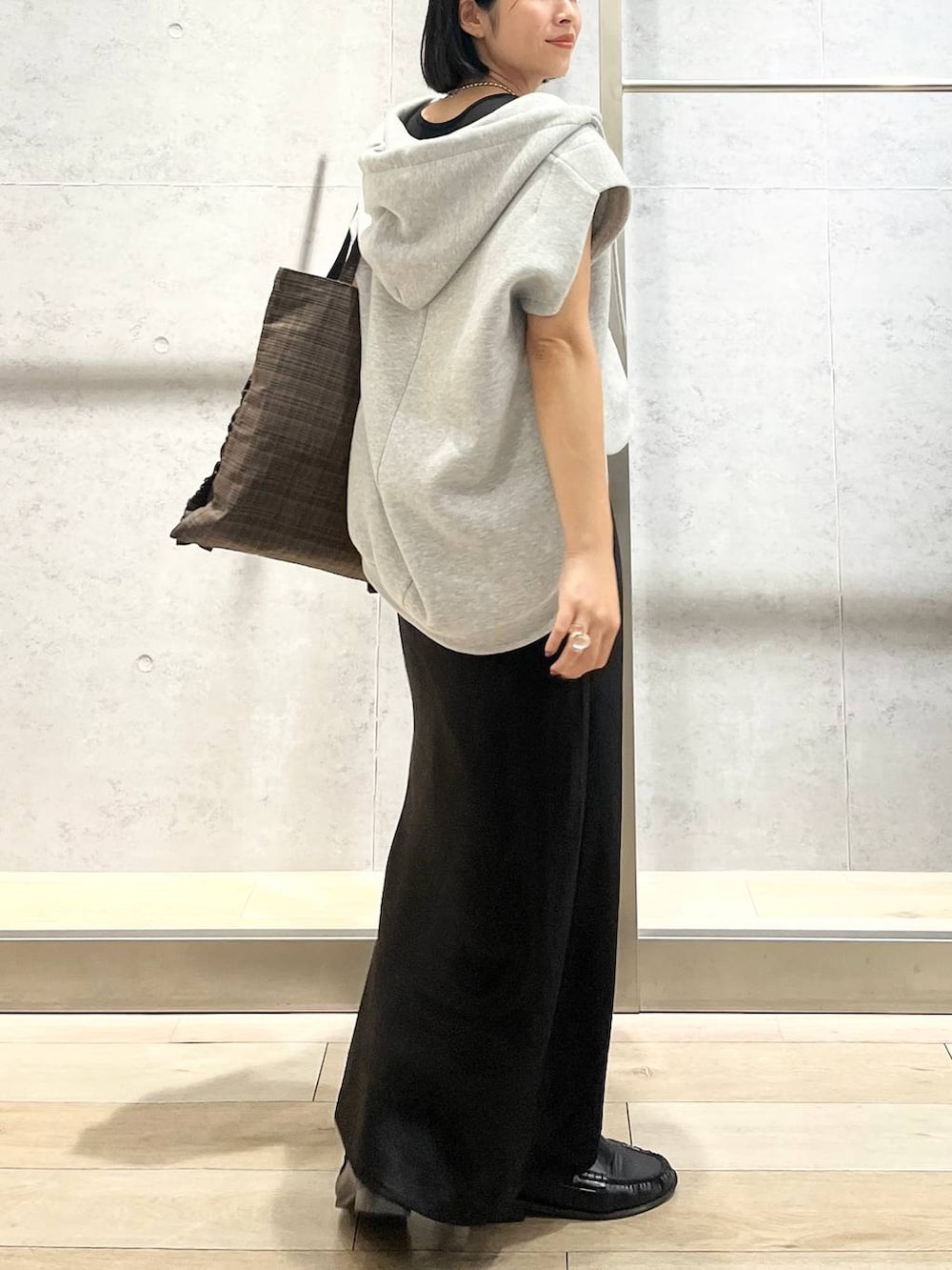 ブラック系のスカート、ブラウン系のトートバッグ、グレー系のベストを着用したレディースの秋コーディネートの4枚目の写真