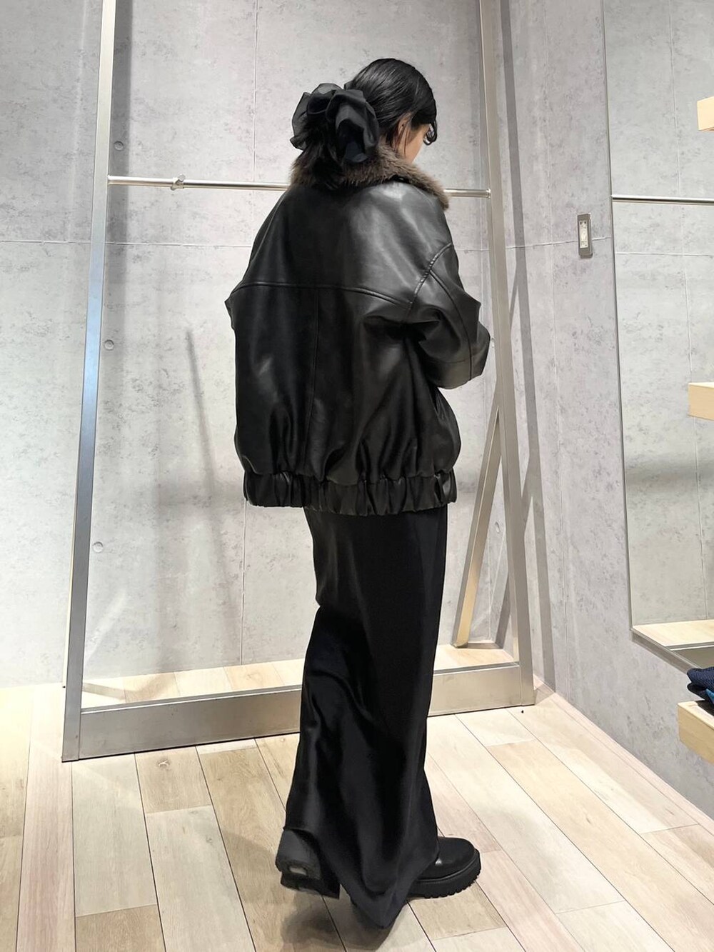 ブラック系のブーツ、オレンジ系のニット/セーター、ブラック系のスカートを着用したレディースの冬コーディネートの3枚目の写真