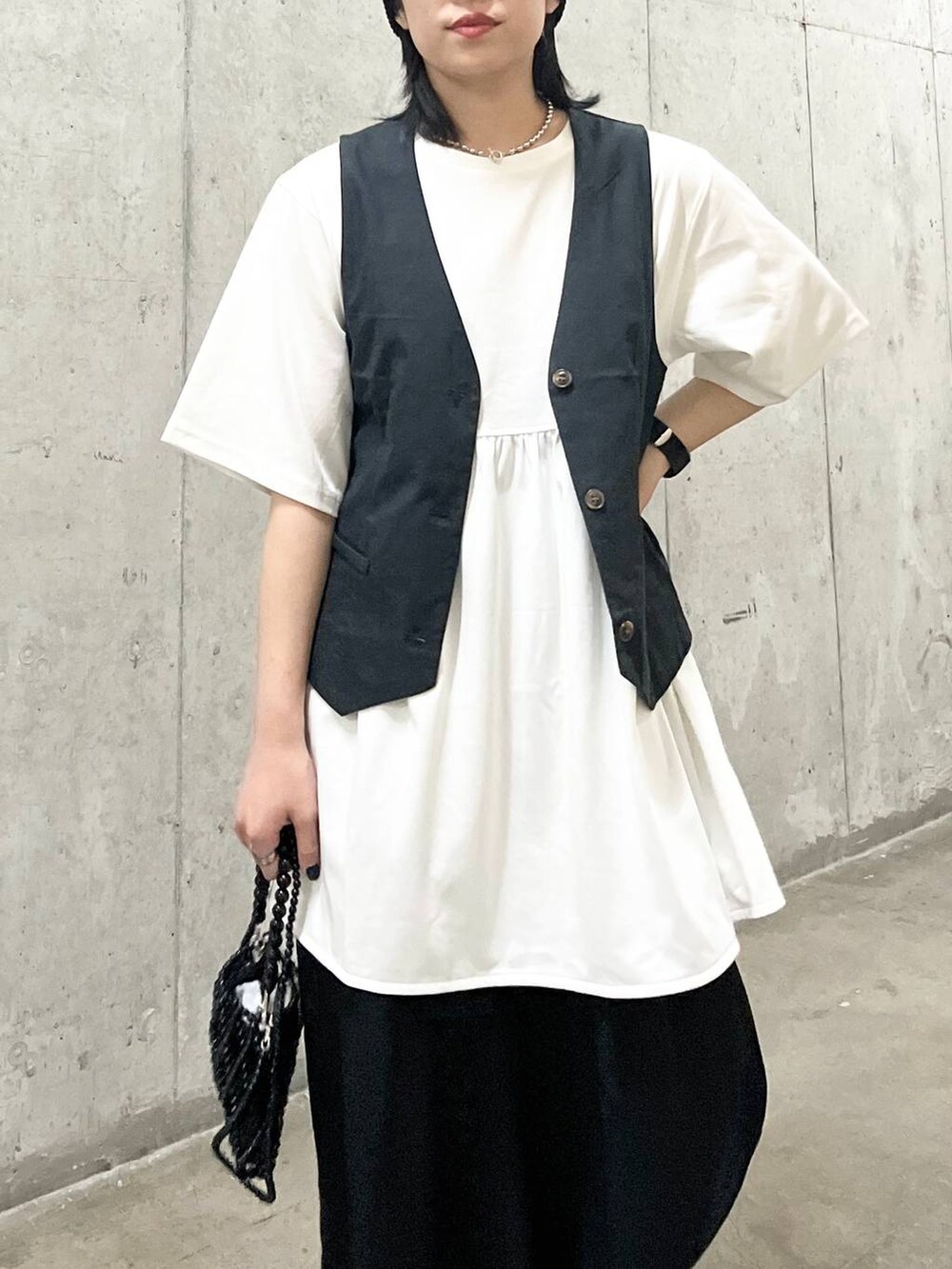 ブラック系のスラックス、ブラック系のショルダーバッグ、グレー系のベストを着用したレディースの夏コーディネートの6枚目の写真