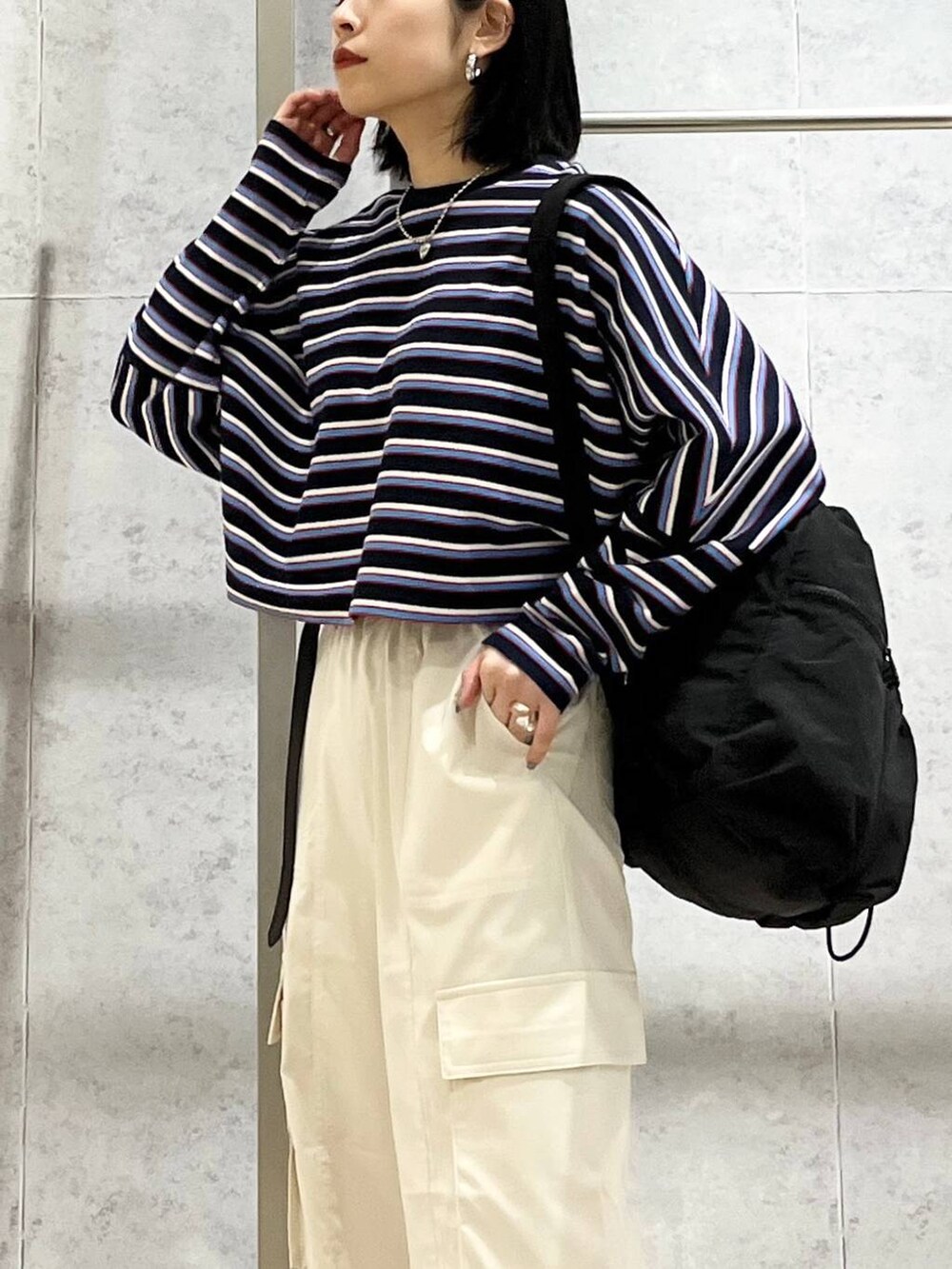 ブラック系のショルダーバッグ、ブルー系のTシャツ/カットソー、ホワイト系のカーゴパンツを着用したレディースの春コーディネートの2枚目の写真