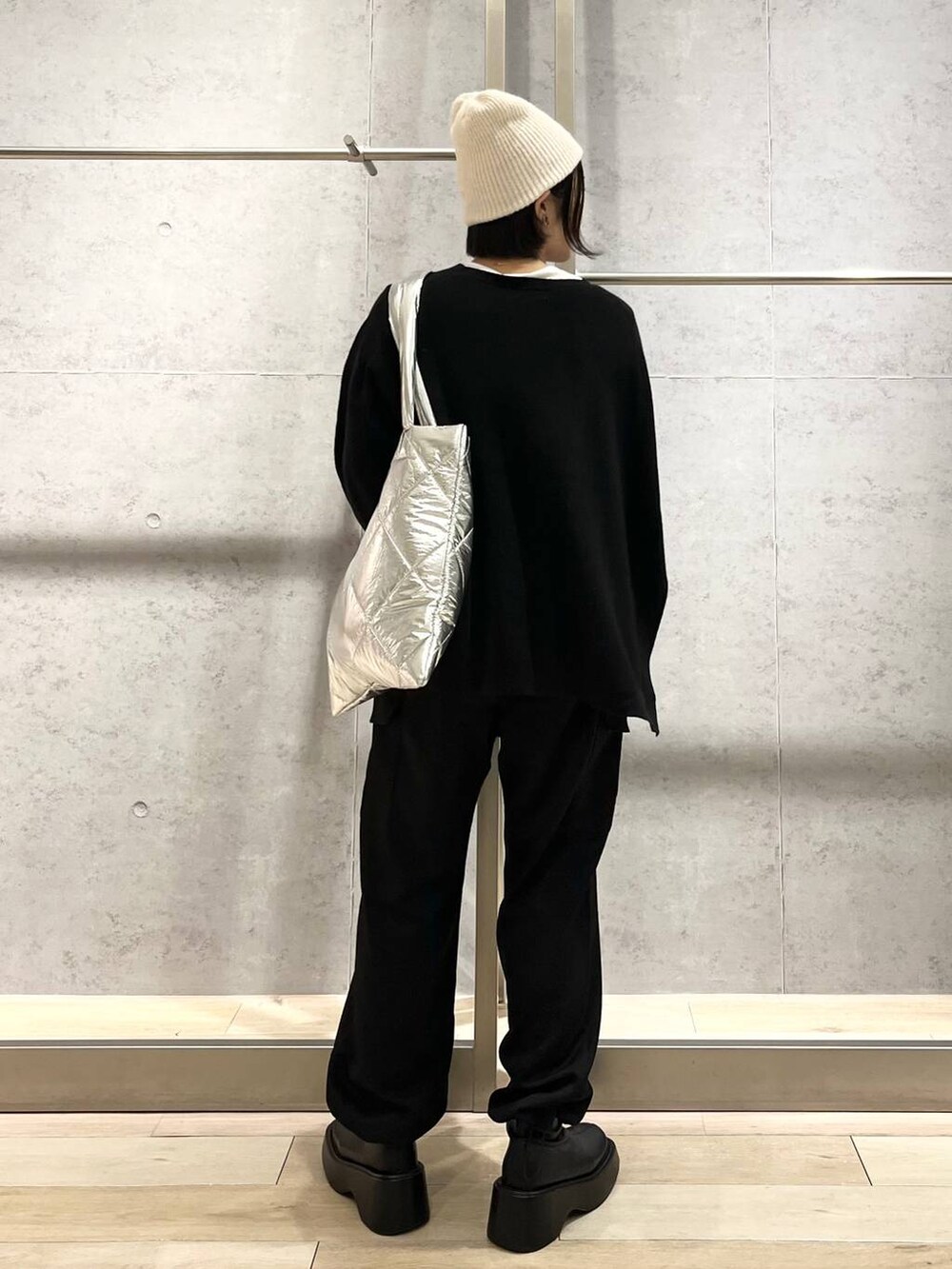 ブラック系のニット/セーター、ホワイト系のTシャツ/カットソー、ブラック系のブーツを着用したレディースの秋コーディネートの5枚目の写真