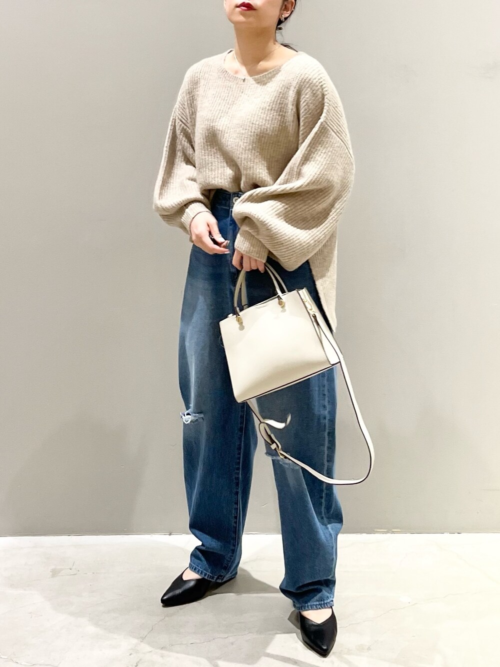 ブルー系のデニムパンツ、ホワイト系のショルダーバッグ、ブラック系のパンプスを着用したレディースの秋コーディネートの2枚目の写真