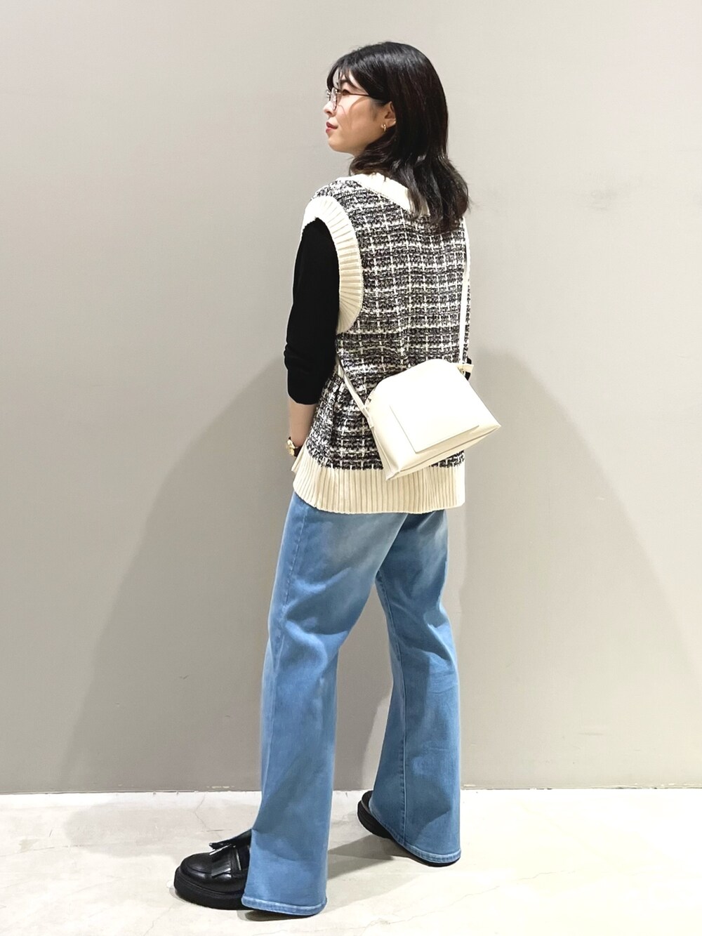 ブルー系のデニムパンツ、ブラック系のローファー、ホワイト系のショルダーバッグを着用したレディースの秋コーディネートの4枚目の写真