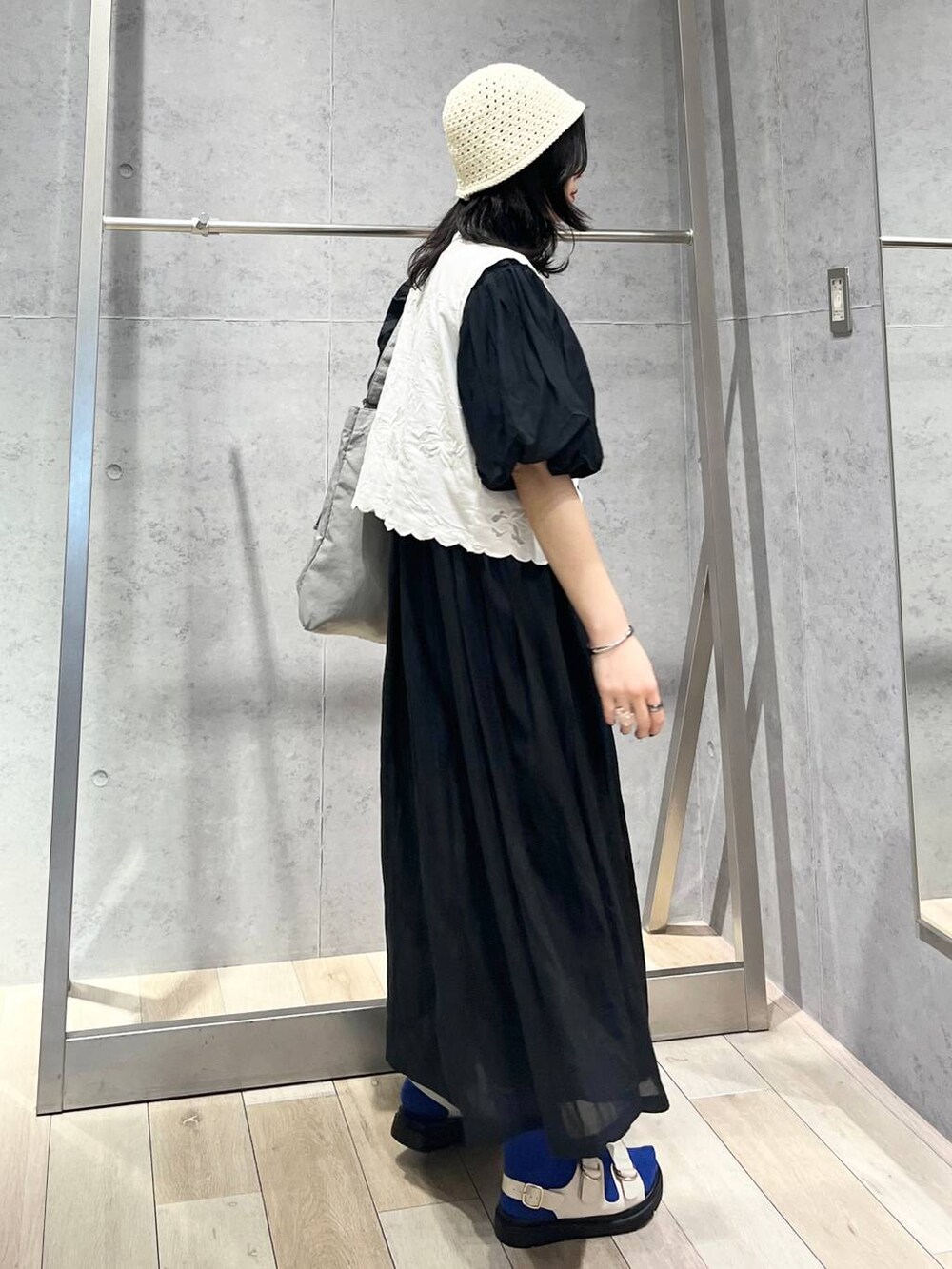 ブラック系のワンピース、ホワイト系のサンダル、ホワイト系のベストを着用したレディースの春コーディネートの3枚目の写真