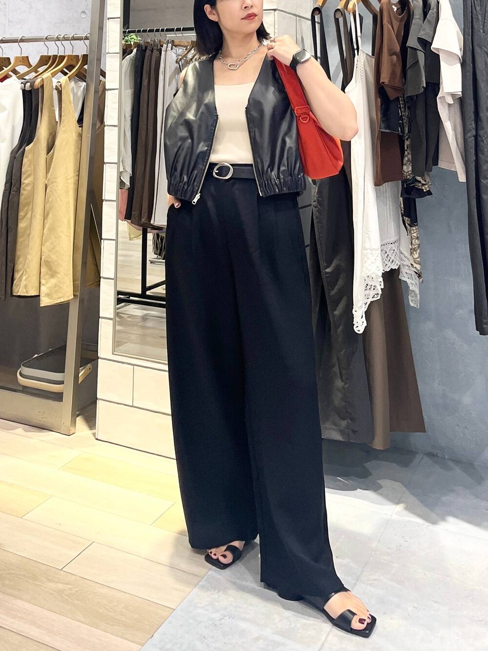 ホワイト系のタンクトップ、ブラック系のその他パンツ、オレンジ系のショルダーバッグを着用したレディースの夏コーディネートの4枚目の写真