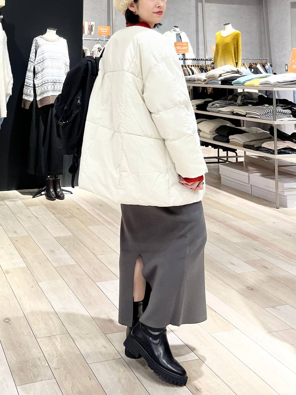 レッド系のニット/セーター、グレー系のスカート、ブラック系のブーツを着用したレディースの冬コーディネートの4枚目の写真