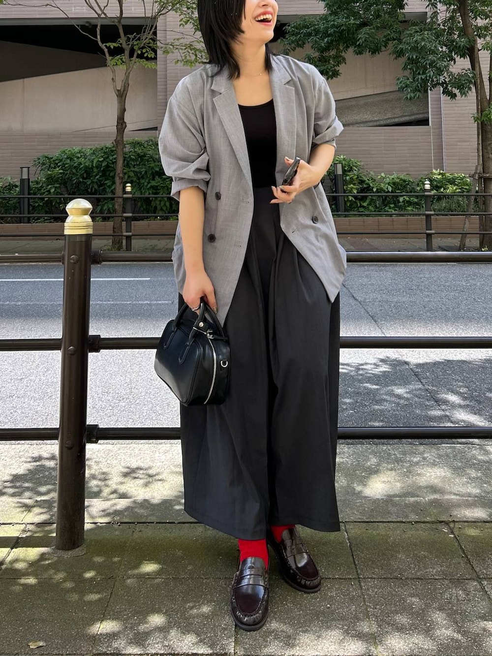 ブラック系のボストンバッグ、グレー系のテーラードジャケット、グレー系のスカートを着用したレディースの夏コーディネートの5枚目の写真