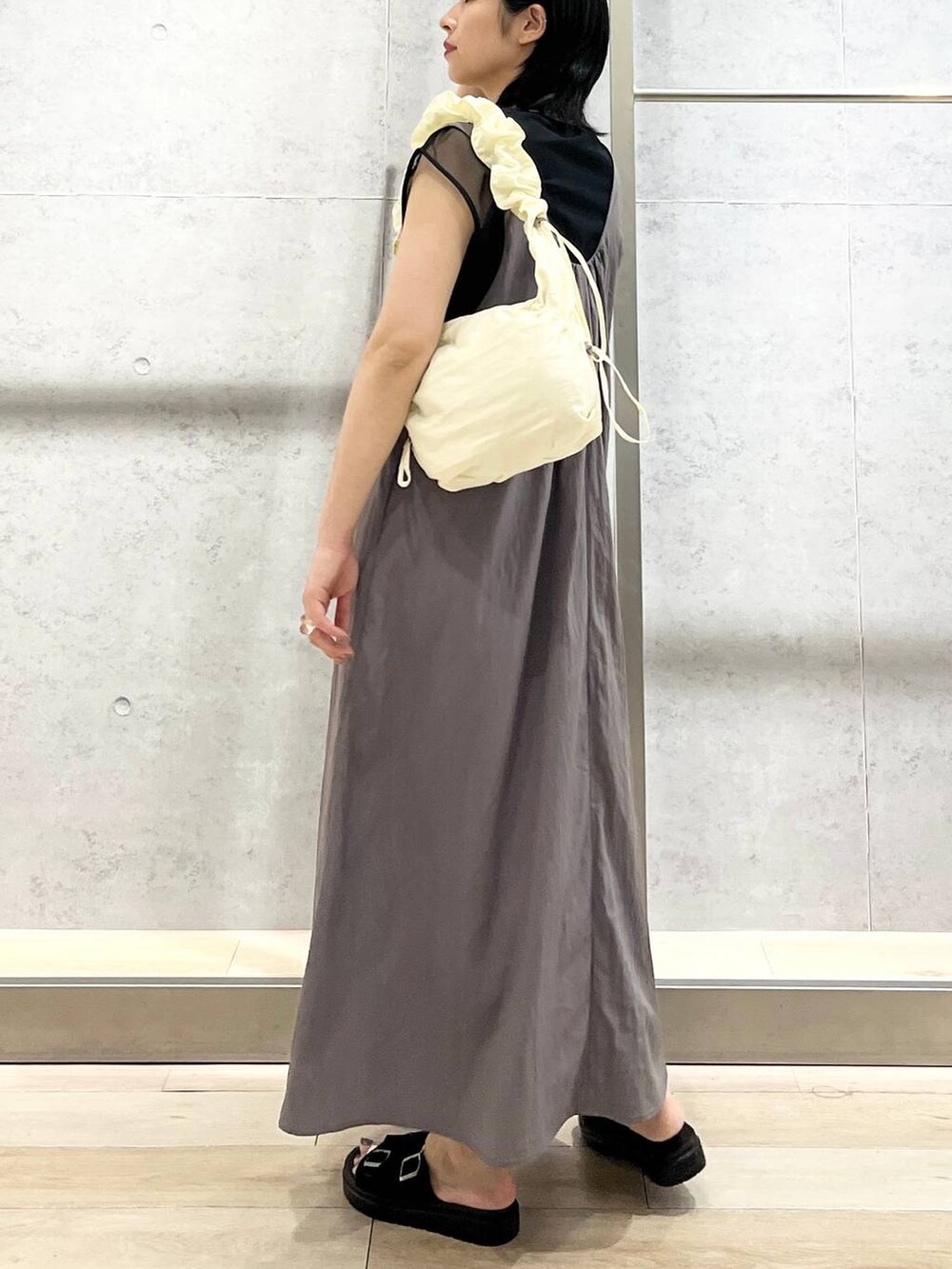 ブラック系のサンダル、グレー系のジャンパースカート、ホワイト系のショルダーバッグを着用したレディースの夏コーディネートの2枚目の写真