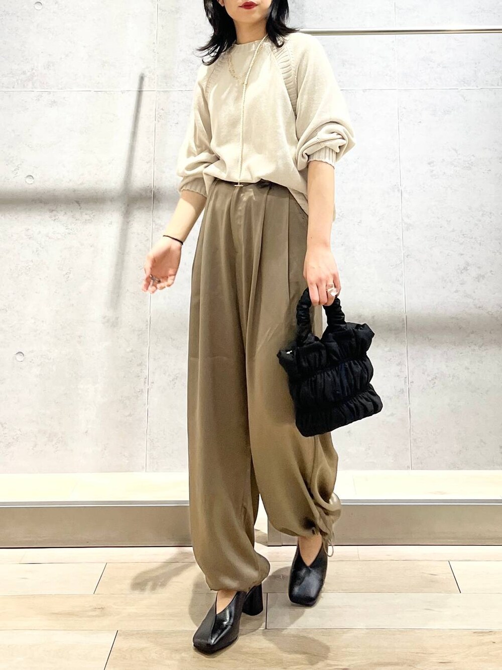 ブラック系のショルダーバッグ、ブラック系のパンプス、イエロー系のその他パンツを着用したレディースの冬コーディネートの2枚目の写真