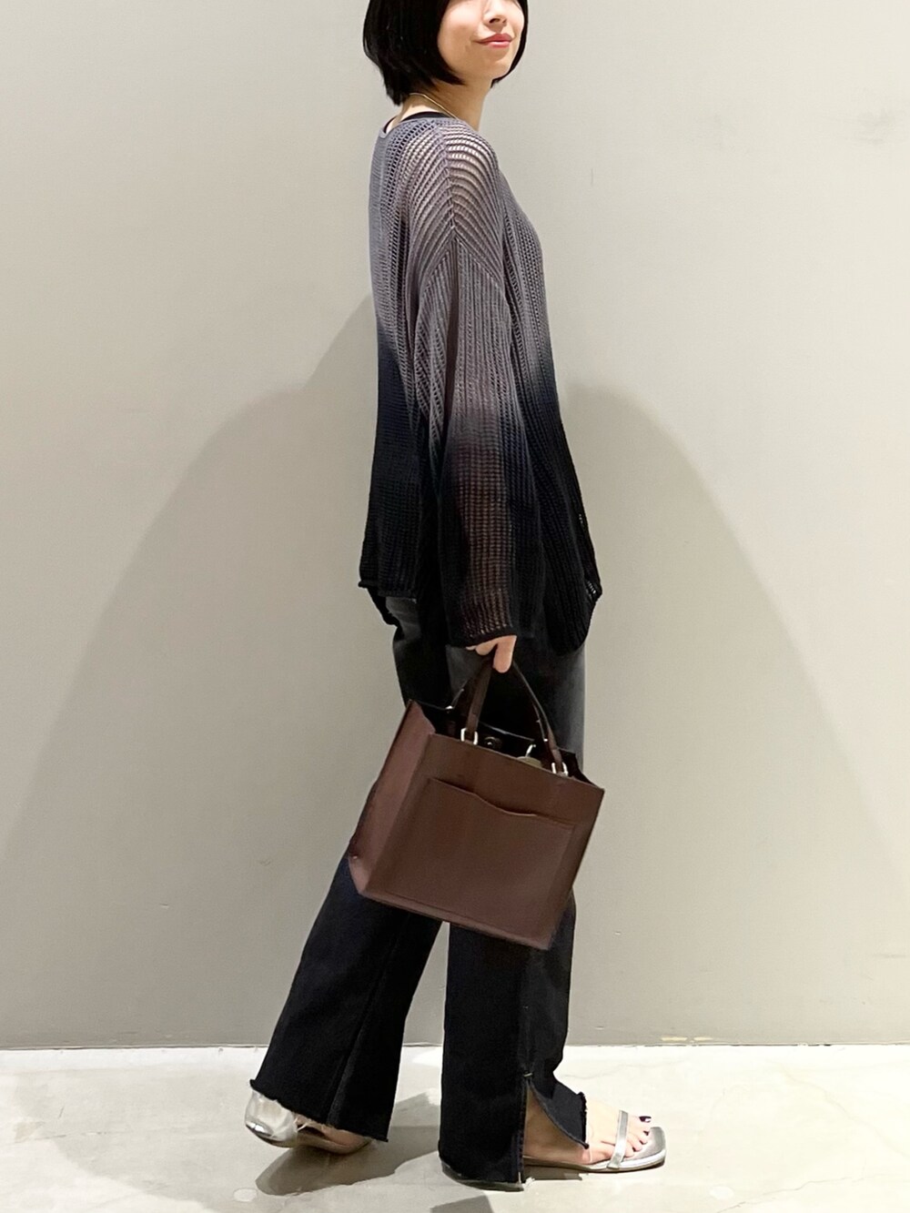 ブラック系のデニムパンツ、ブラウン系のバッグ、シルバー系のサンダルを着用したレディースの夏コーディネートの3枚目の写真