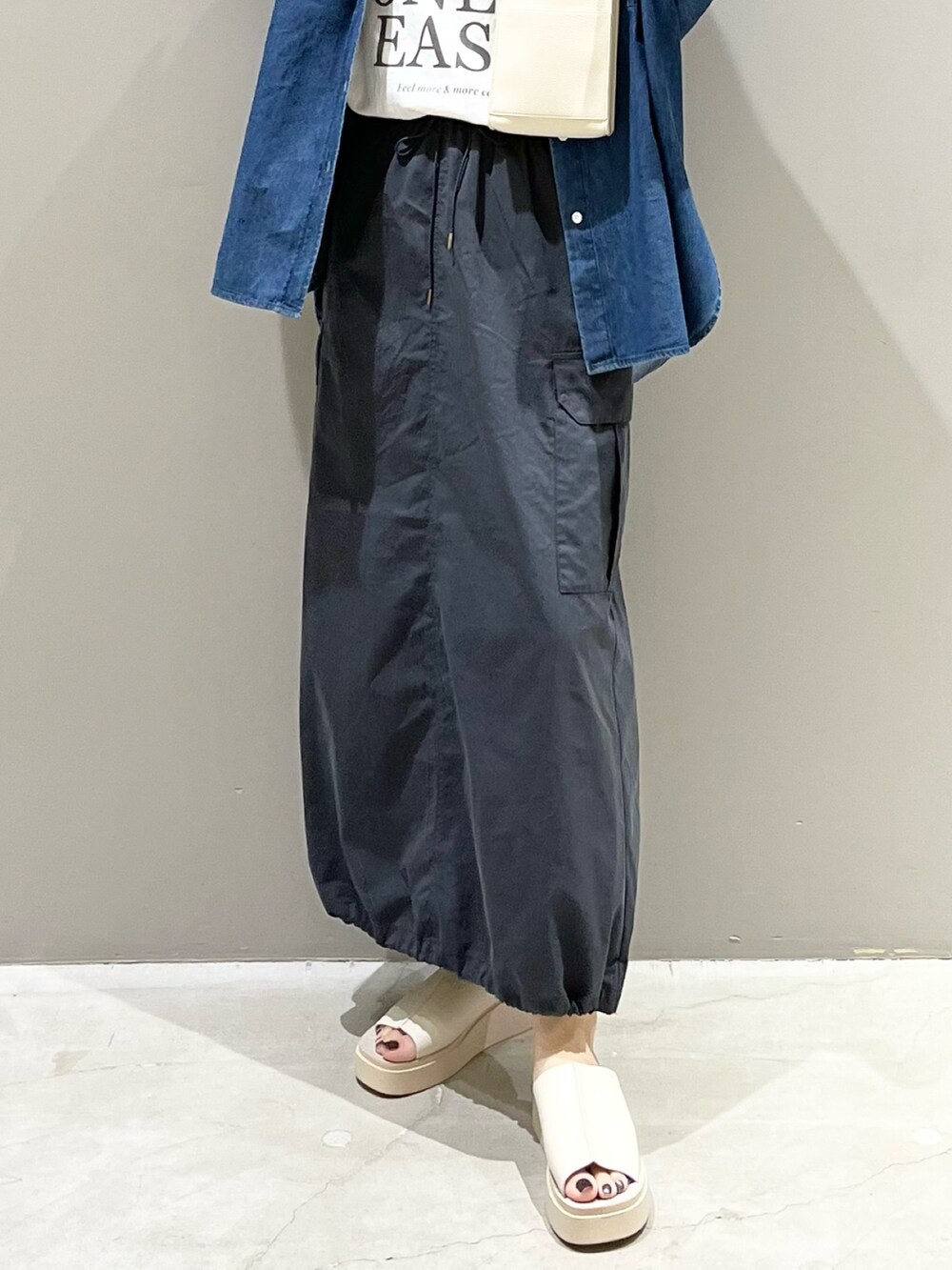 オレンジ系のバッグ、グレー系のスカート、ベージュ系のサンダルを着用したレディースの夏コーディネートの7枚目の写真