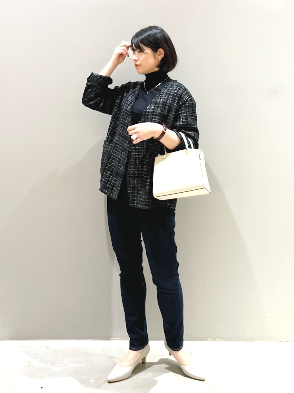 ホワイト系のショルダーバッグ、ベージュ系のパンプス、ブルー系のデニムパンツを着用したレディースの春コーディネートの2枚目の写真