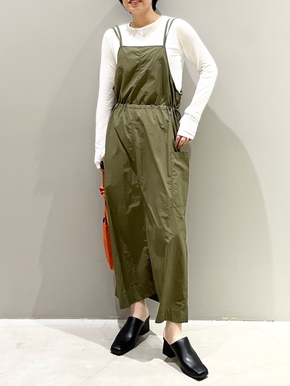 グリーン系のワンピース、オレンジ系のバッグ、ブラック系のサンダルを着用したレディースの春コーディネートの9枚目の写真