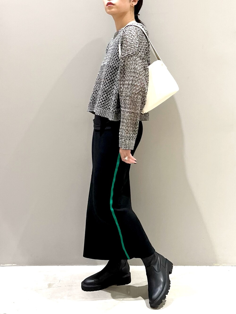 ブラック系のニット/セーター、ホワイト系のショルダーバッグ、ブラック系のブーツを着用したレディースの秋コーディネートの2枚目の写真