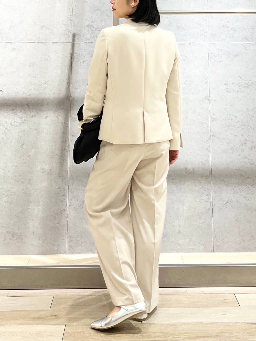 ブラック系のハンドバッグ、ブルー系のシャツ/ブラウス、ホワイト系のノーカラージャケットを着用したレディースの冬コーディネートの4枚目の写真