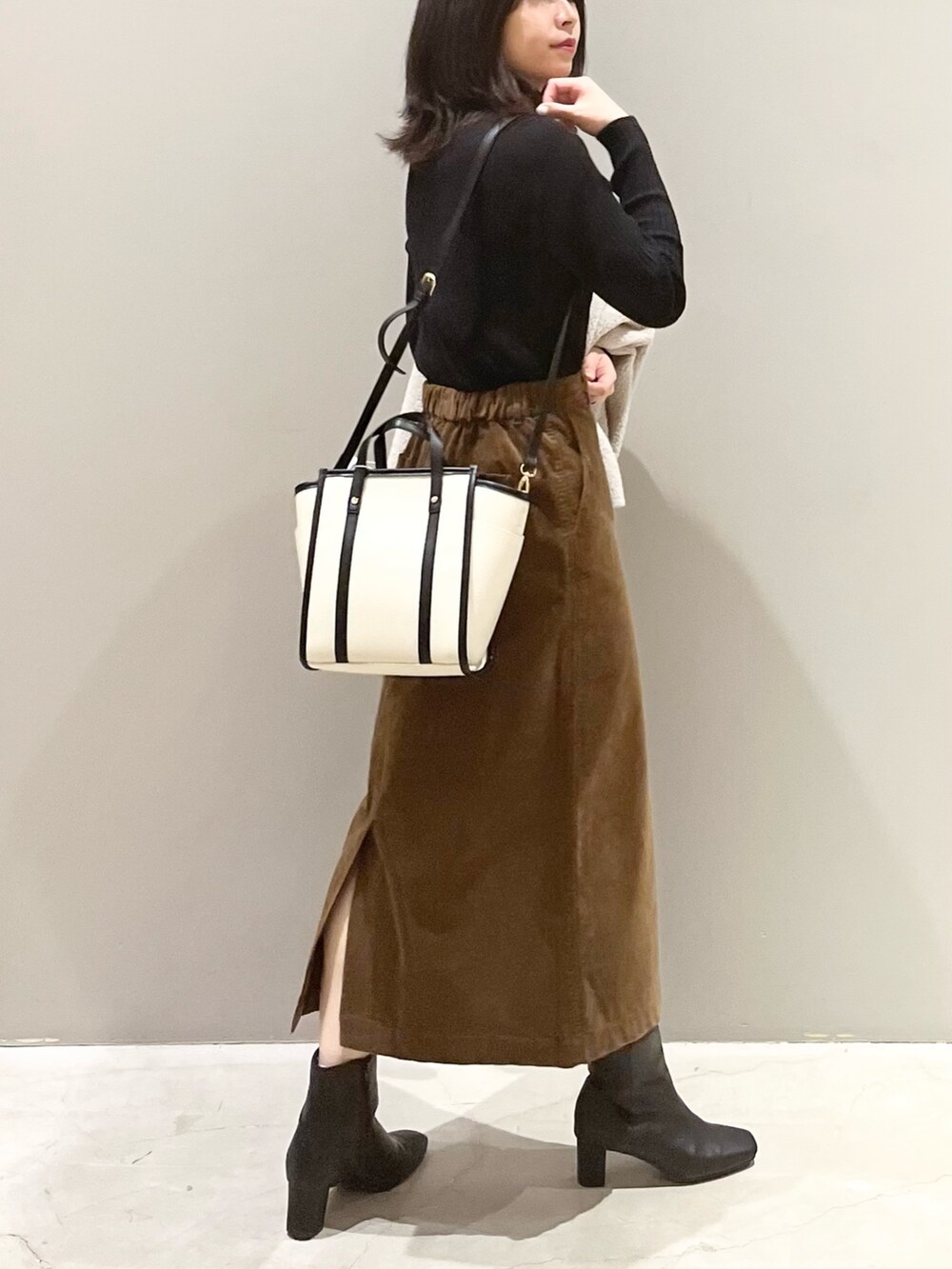 ブラック系のブーツ、ブラウン系のスカート、ホワイト系のショルダーバッグを着用したレディースの秋コーディネートの5枚目の写真