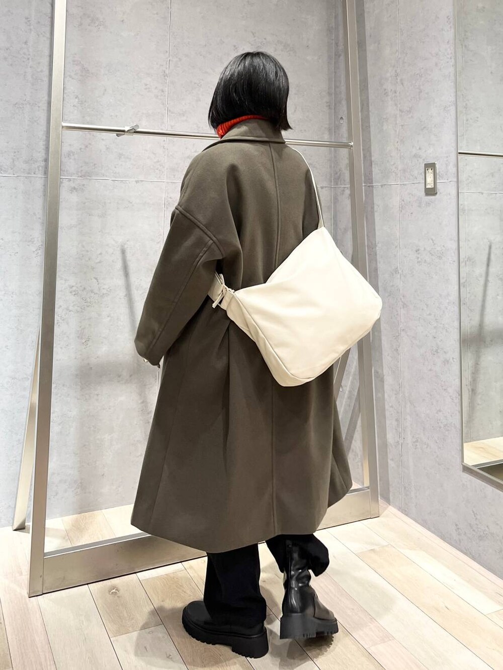 レッド系のニット/セーター、グリーン系のチェスターコート、ブラック系のブーツを着用したレディースの冬コーディネートの4枚目の写真