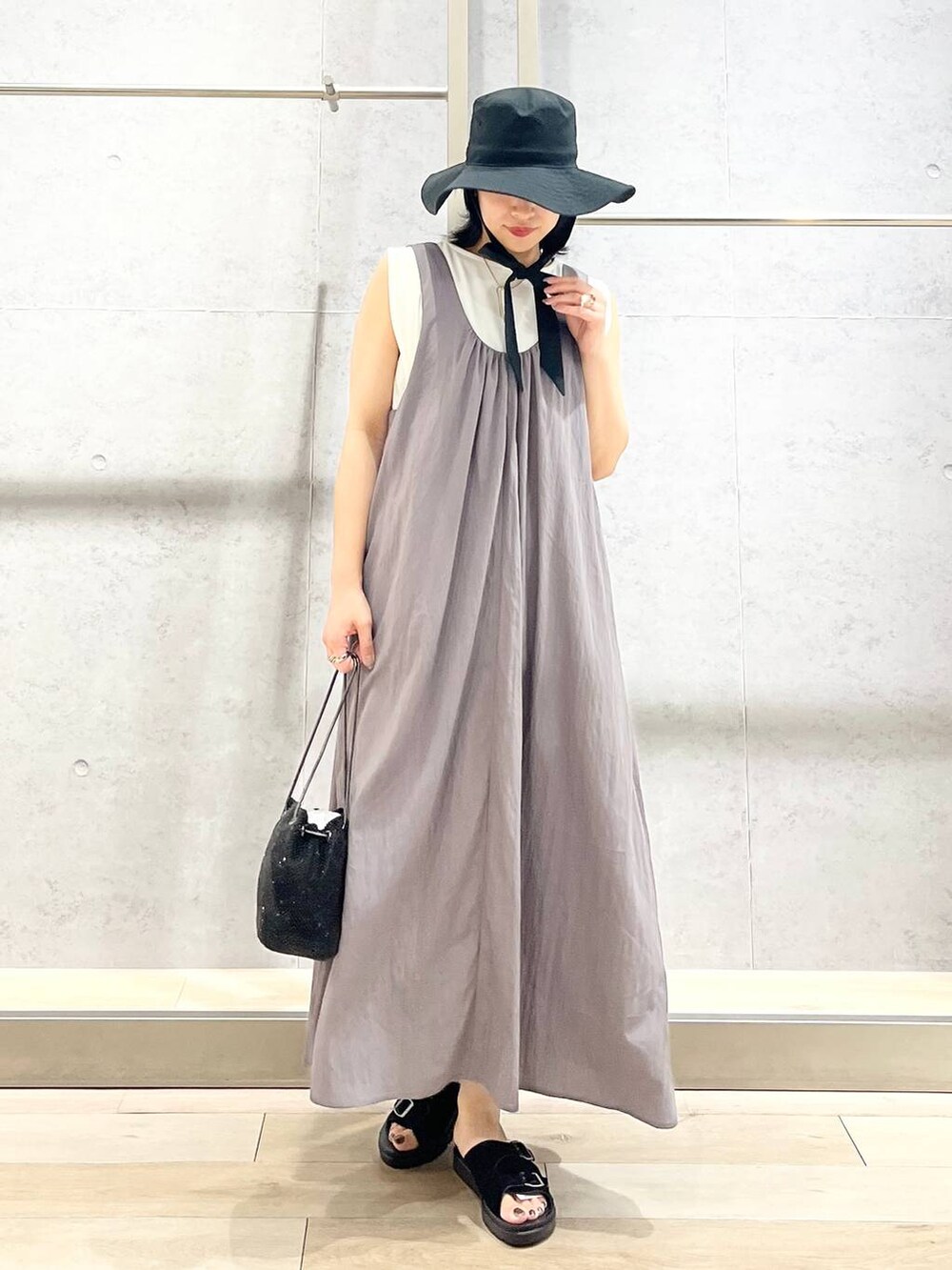 ブラック系のショルダーバッグ、ブラック系のサンダル、ホワイト系のTシャツ/カットソーを着用したレディースの夏コーディネートの7枚目の写真