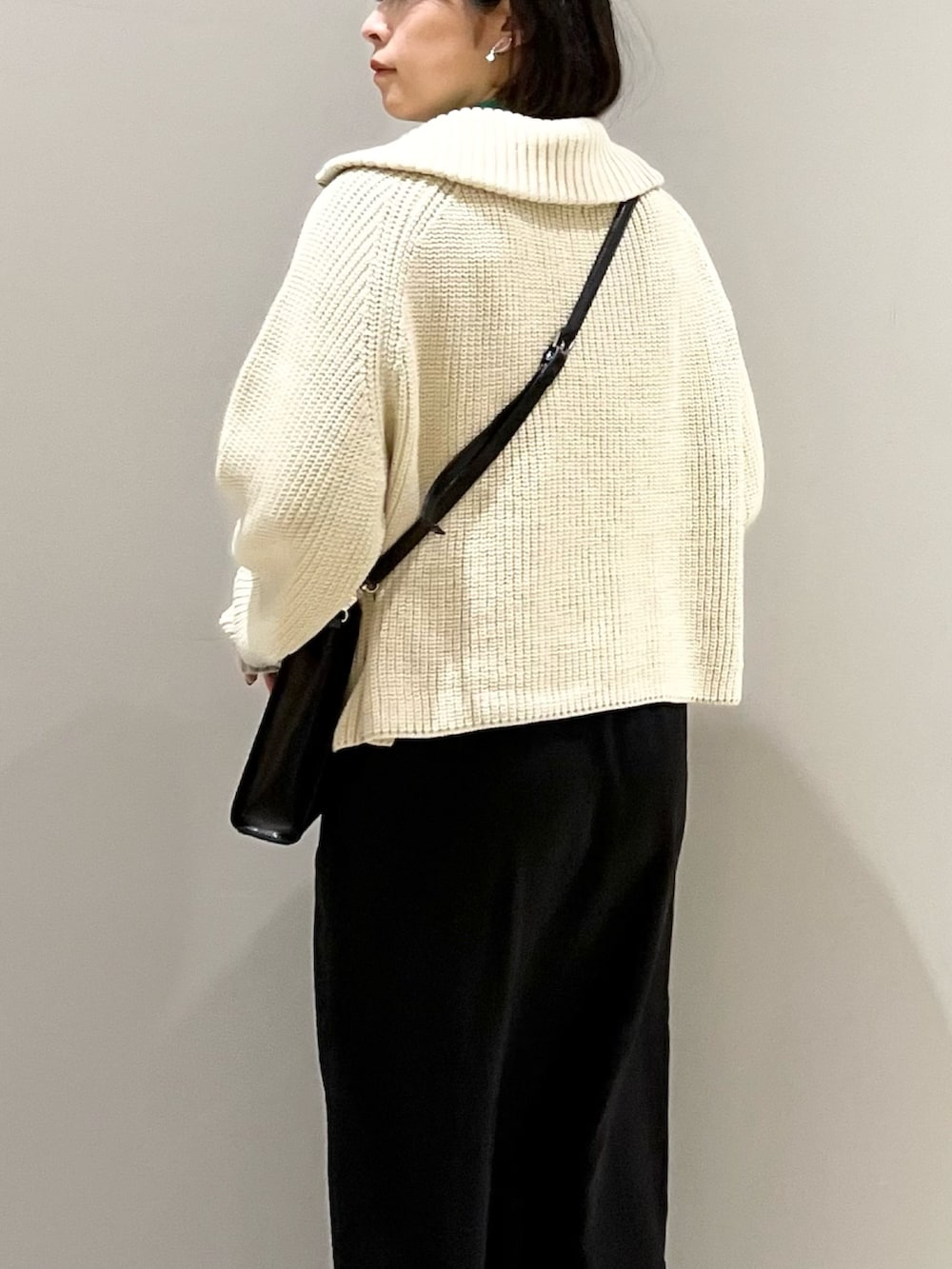 ブラック系のスカート、ブラック系のショルダーバッグ、ブラック系のブーツを着用したレディースの冬コーディネートの5枚目の写真