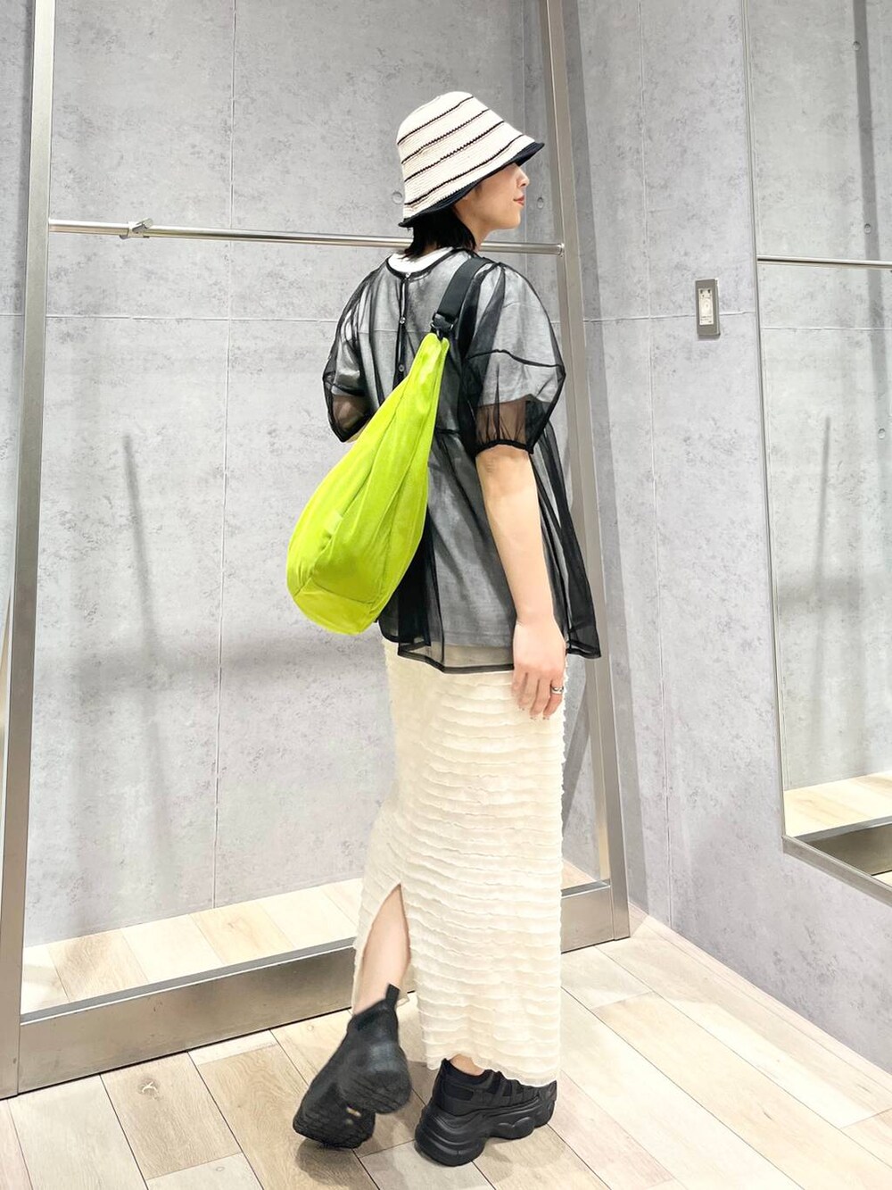 ブラック系のスニーカー、ホワイト系のスカート、グリーン系のショルダーバッグを着用したレディースの春コーディネートの3枚目の写真