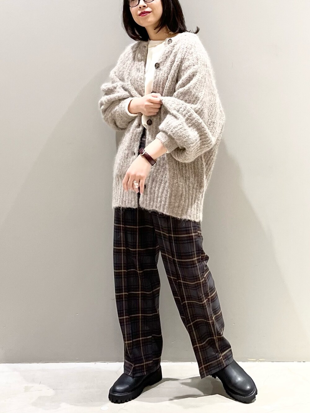 ブラウン系のスラックス、ブラック系のブーツ、ベージュ系のカーディガン/ボレロを着用したレディースの冬コーディネートの3枚目の写真