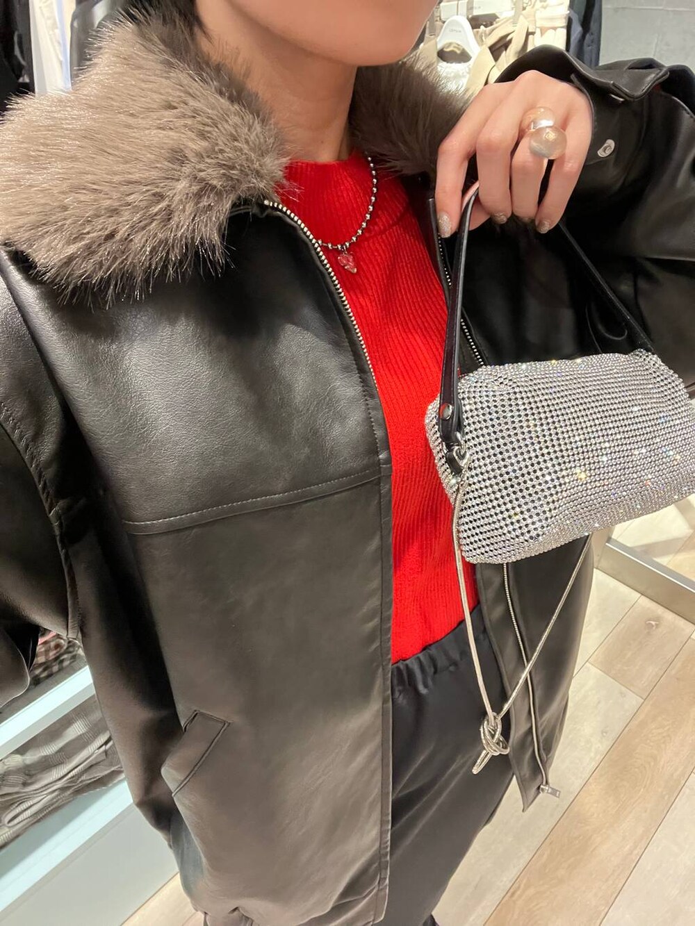 ブラック系のブーツ、オレンジ系のニット/セーター、ブラック系のスカートを着用したレディースの冬コーディネートの5枚目の写真