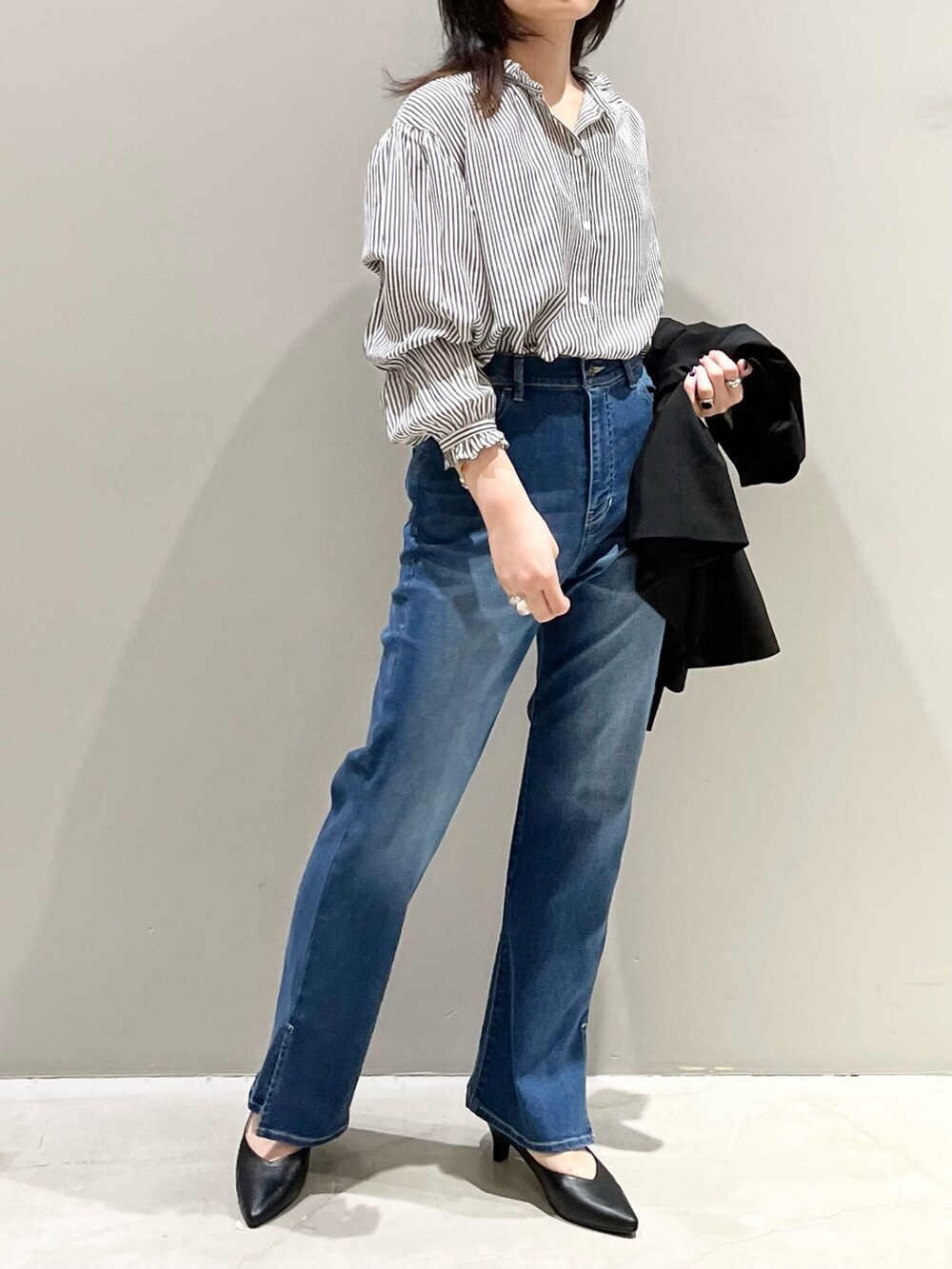 ブルー系のデニムパンツ、ブラック系のパンプス、ホワイト系のショルダーバッグを着用したレディースの秋コーディネートの3枚目の写真