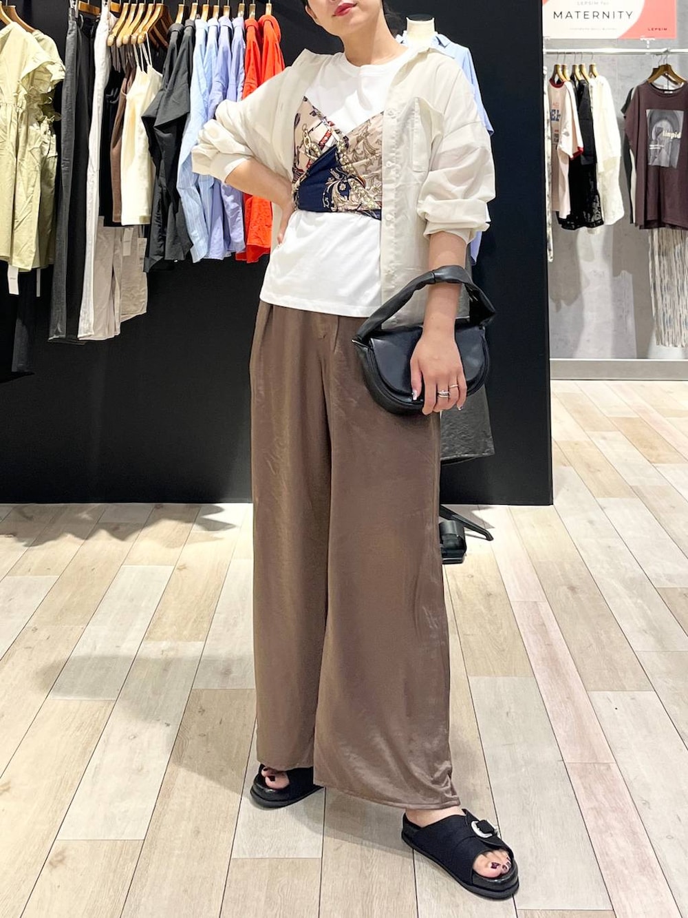 ブラック系のハンドバッグ、ブラック系のサンダル、ホワイト系のシャツ/ブラウスを着用したレディースの夏コーディネートの5枚目の写真