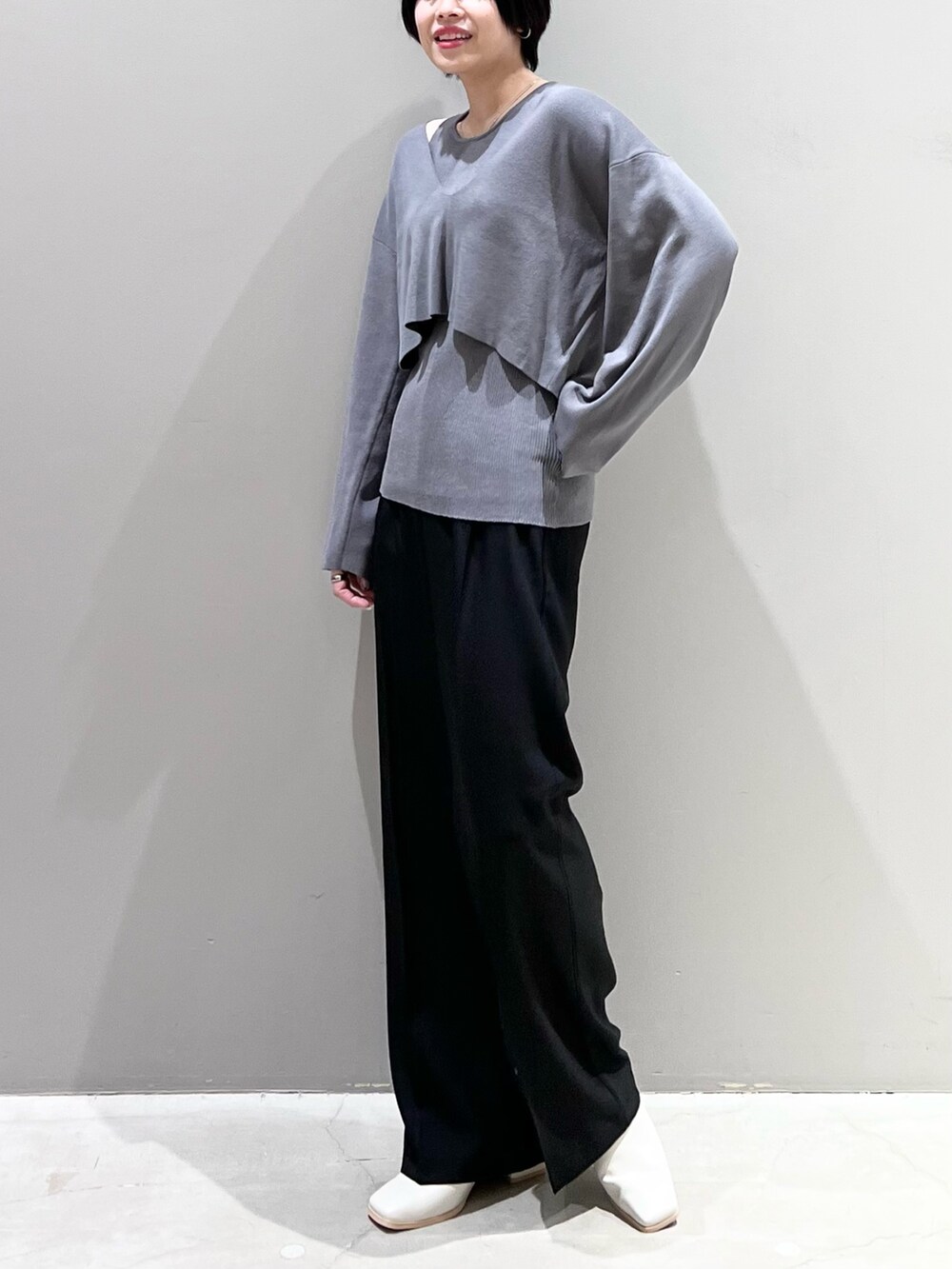 グレー系のニット/セーター、ブラック系のパンツ、ホワイト系のシューズを着用したレディースの春コーディネートの2枚目の写真