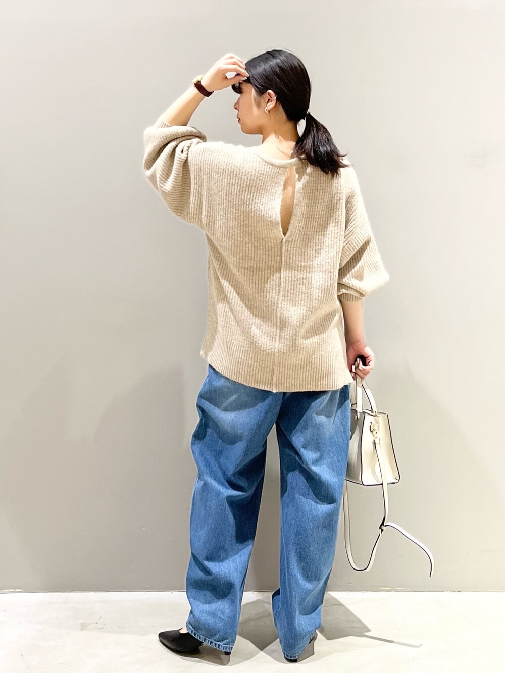 ブルー系のデニムパンツ、ホワイト系のショルダーバッグ、ブラック系のパンプスを着用したレディースの秋コーディネートの3枚目の写真