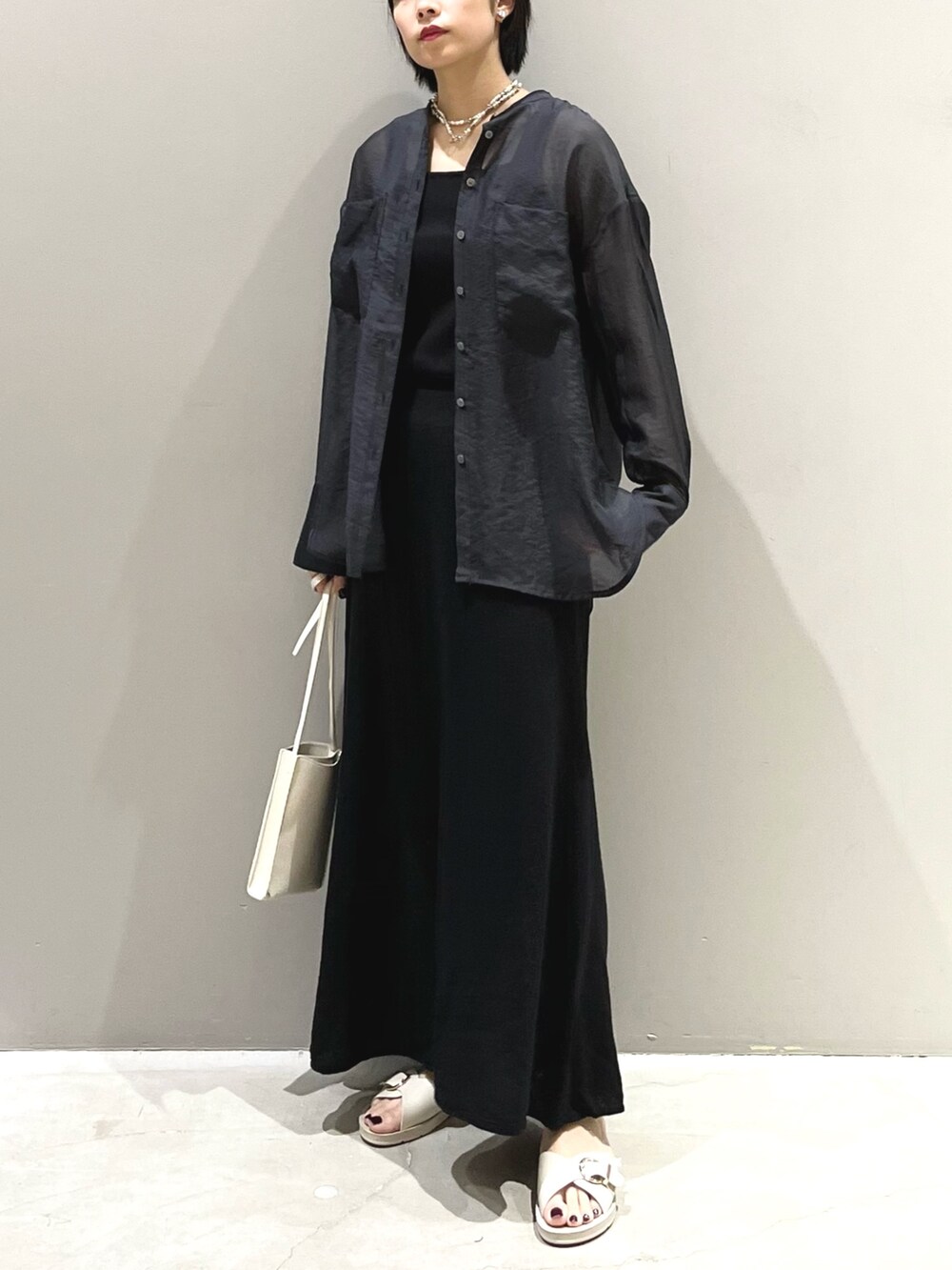 ホワイト系のサンダル、オレンジ系のバッグ、ブラック系のスカートを着用したレディースの夏コーディネートの3枚目の写真