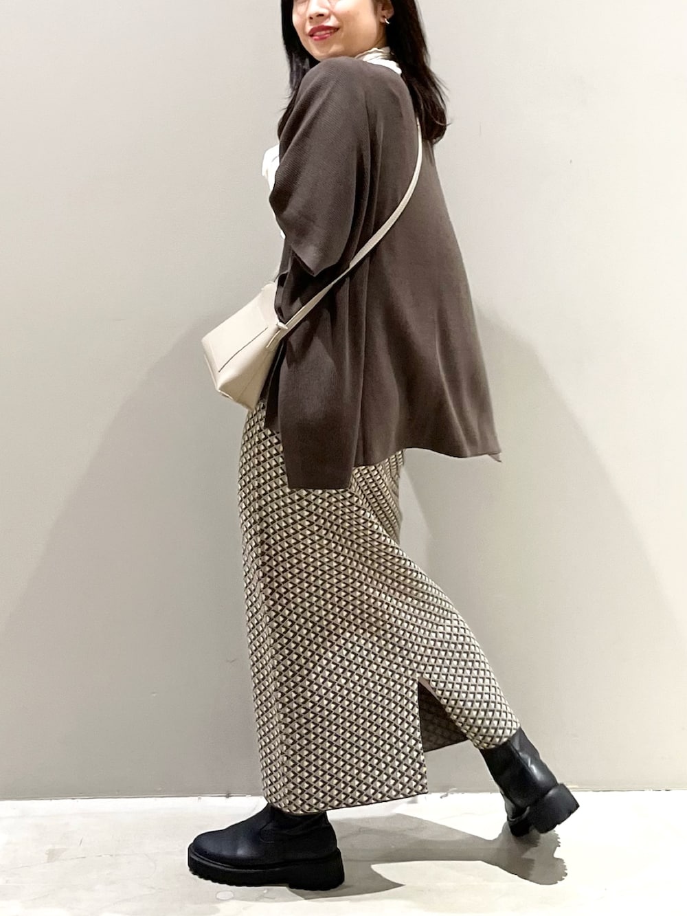 ブラウン系のスカート、ブラック系のブーツ、ブラウン系のニット/セーターを着用したレディースの秋コーディネートの4枚目の写真