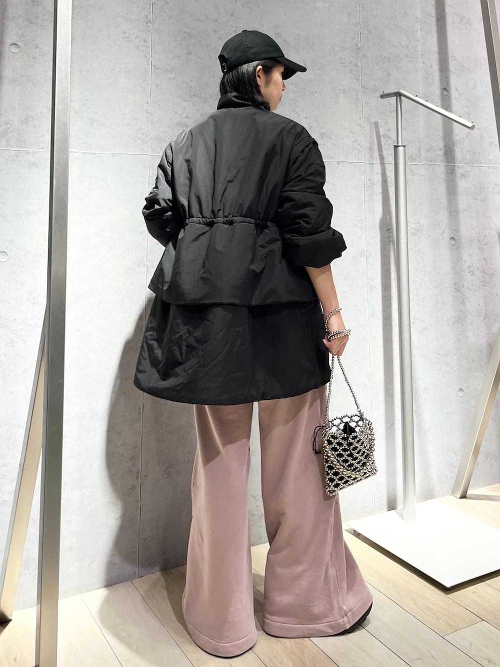 シルバー系のショルダーバッグ、ピンク系のスウェットパンツ、ブラック系のキャップを着用したレディースの秋コーディネートの4枚目の写真