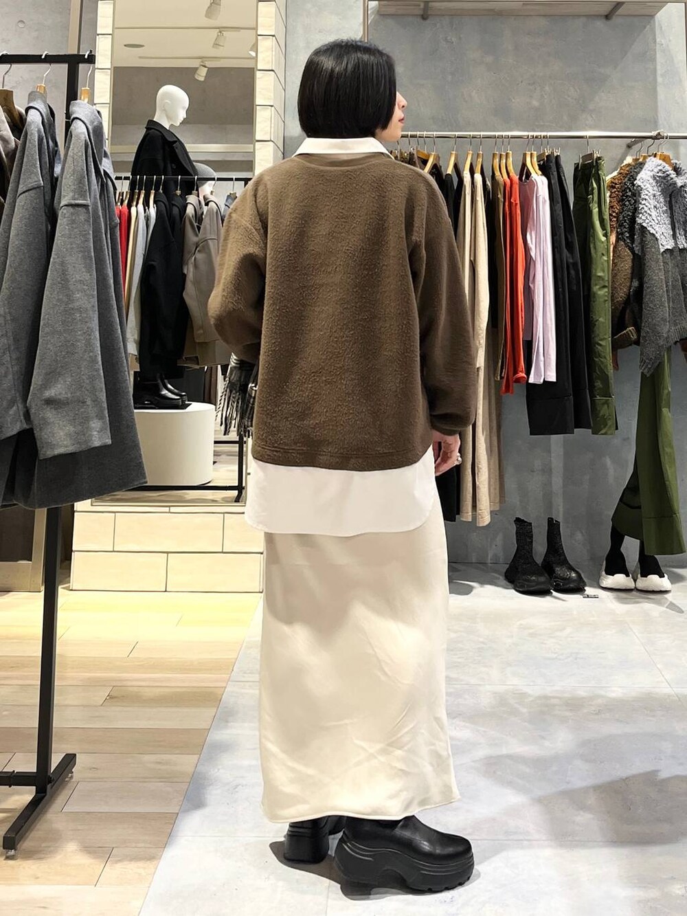 ホワイト系のスカート、ブラック系のブーツ、イエロー系のTシャツ/カットソーを着用したレディースの冬コーディネートの4枚目の写真